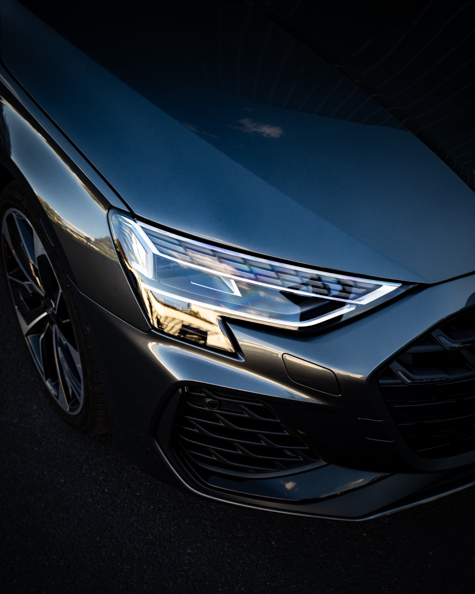 Audi-Scheinwerfer und Karosserie mit Spiegelungen im Lack