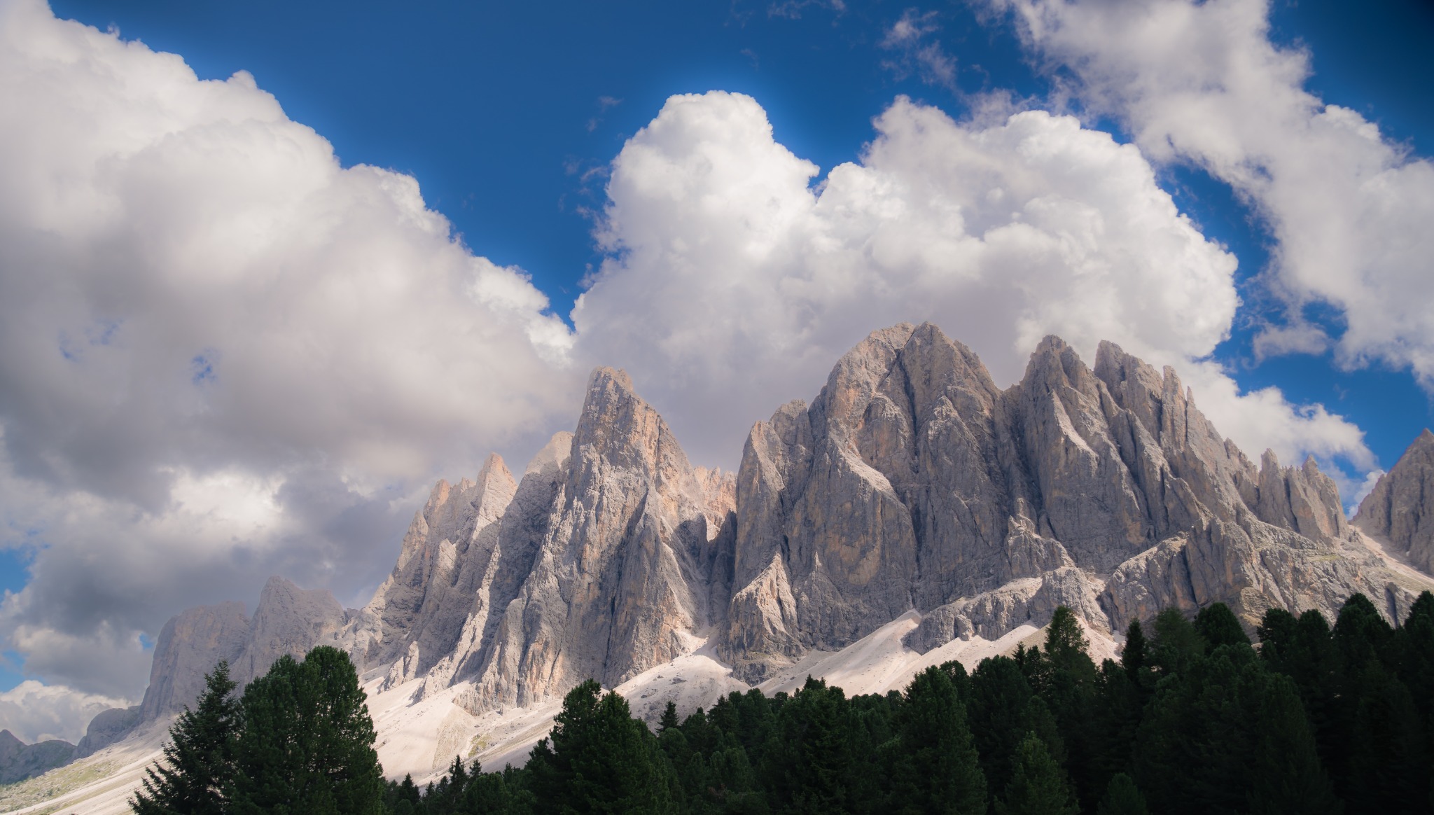 Helle Bergspitzen unter großen Wolken und blauem Himmel