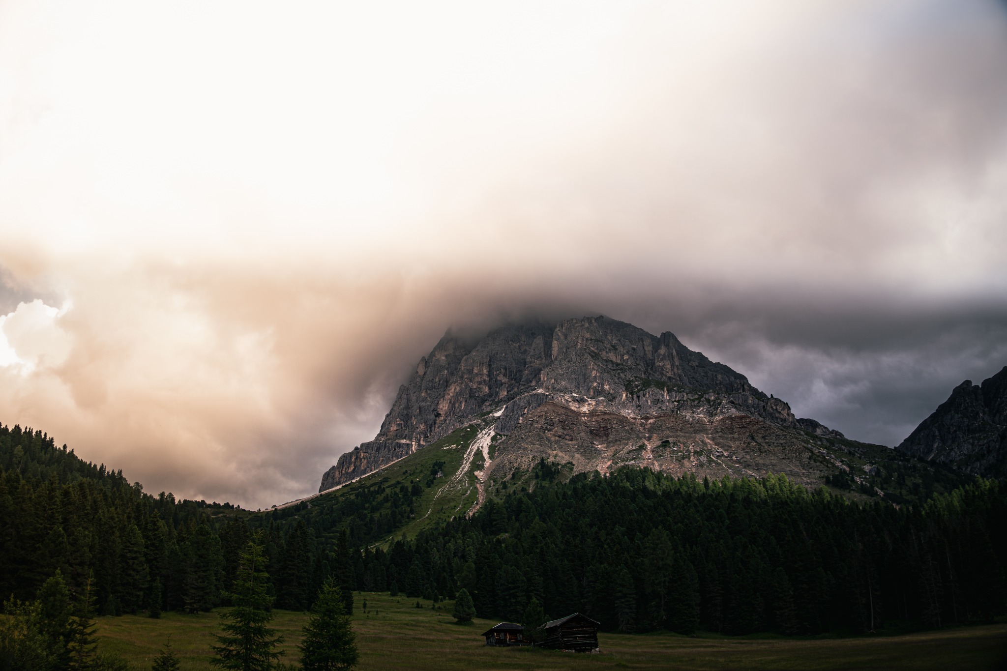 Wolken und warmes Licht über einem Berg und bewaldeten Tal
